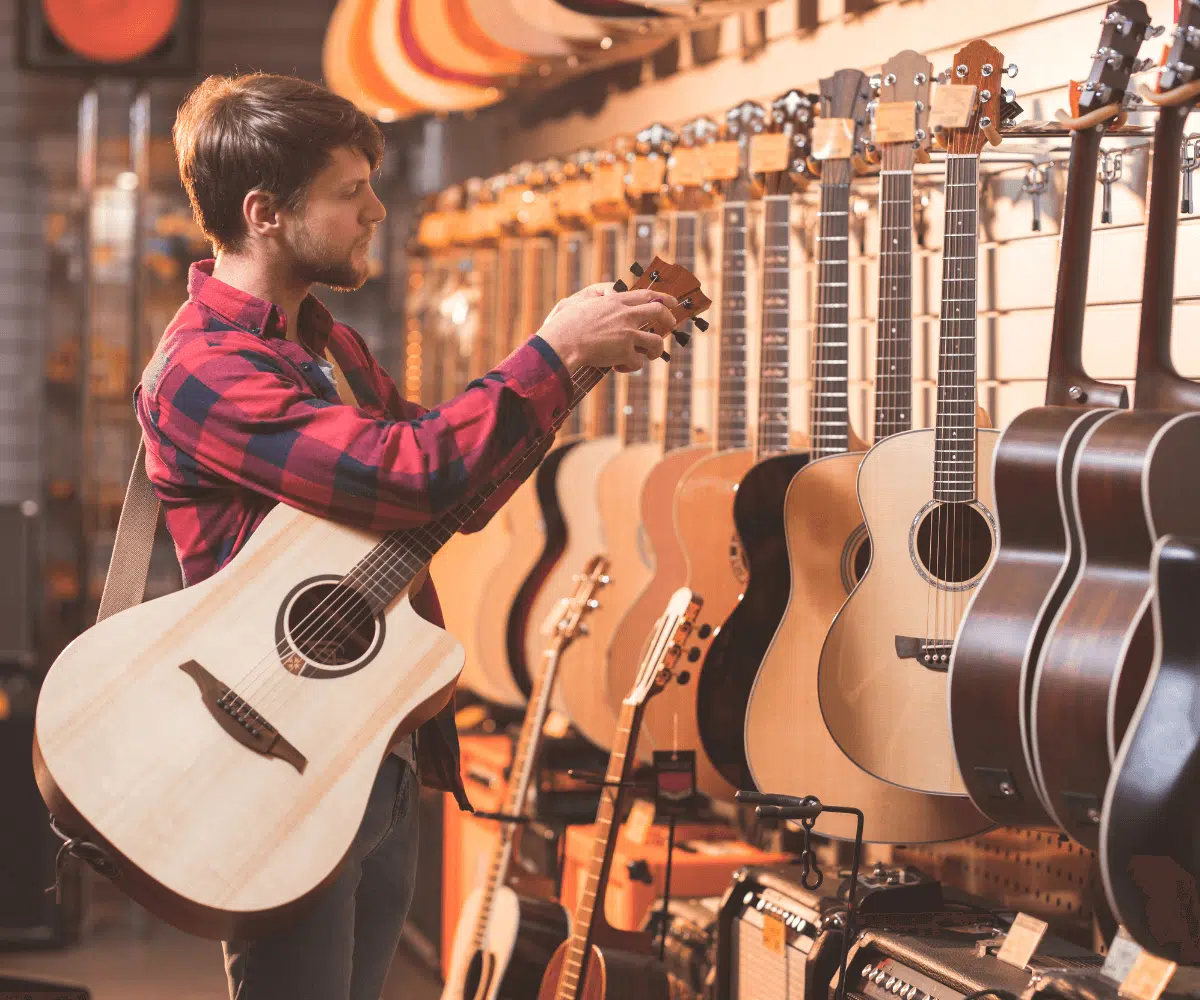 Un homme choisi sa première guitare dans une boutique d'instruments de musique.